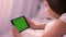 Closeup portrat of young caucasian female laughing while playing video on the tablet with green chroma-key screen