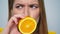 Closeup positive woman making funny faces with orange in hands in studio.