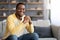 Closeup of positive young black man chilling on sofa