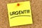 Closeup post it note on corkboard with urgent message on it