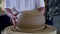 Closeup potter man grinds big ceramic vessel with metal ring