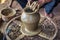 Closeup of potter`s hands making clay water pot on pottery wheel.