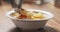 Closeup pouring cauliflower soup into bowl on wood table