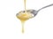 Closeup pouring condensed milk with teaspoon on white background