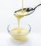 Closeup pouring condensed milk with teaspoon on white background