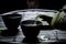 Closeup of pouring green tea in teacup on black table