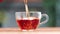 Closeup pouring stream fresh aroma hot black tea into transparent glass cup teapot serving table