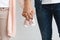 Closeup of pregnant couple carrying small baby shoes while holding hands together