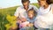 Closeup pregnant couple with toddler daughter have leisure time outdoors in grass field on blanket