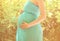 Closeup pregnant woman in dress in summer