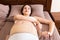 Closeup pregnant woman dresses bandage on belly at home on bed. Orthopedic abdominal support belt