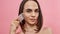 Closeup of pretty young transgender with dark brown hair using rose quartz gua sha stone for facial massage, posing