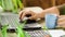 Closeup professional freelancer drinks coffee, using laptop and working at table on rooftop terrace