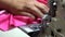 Closeup of a professional seamstress sewing a pink dress