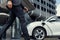 Closeup progressive businessman with EV car at public charging station.