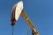 Closeup of a pumpjack in an oil field agaist a bright blue sky