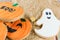 Closeup of pumpkin and ghost-shaped buttery cookies on a brown paper