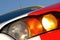 A closeup of a race cars left headlight with the colorful red and white detailing and the powerful shape. Speed drive