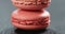Closeup of raspberry red macarons stacked on slate board