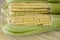 Closeup of raw corn cobs with straw over wood