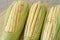 Closeup of raw corn cobs with straw over wood