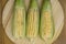 Closeup of raw corn cobs with straw over wood