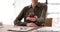 Closeup realtor sitting at table and holding model of tiny house and layout of cottage