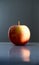 Closeup of a red apple reflecting on the table under the lights with a blurry background