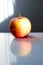 Closeup of a red apple reflecting on the table under the lights with a blurry background