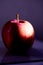 Closeup of a red apple reflecting on the table under the lights with a blurry background