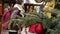 Closeup of a red Christmas ball hang on a natural New Year tree on a city fair, crowd of people walking on a festive city square o