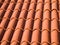 Closeup of the red clay roof tiles. Shingles. Old and used overlapping red classic style roofing material texture