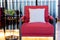 Closeup red cotton armchair with cushion near black coffee table in living room.