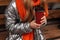 Closeup of a red cup with tasty tea in female hands. Trendy red-haired girl with a knitted scarf in a fashionable shiny jacket is