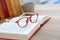 Closeup of red eyeglasses, books and cup of coffee