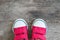 Closeup red fabric sneakers of kid on old wood floor textured background in top view with copy space