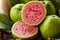 Closeup on red guava sliced with green leaf on rustic wooden background