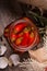 Closeup of red piquant chili papper in a glass jar, twigs of rosemary and shells of quail eggs on a wooden background.