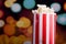 Closeup red white striped container standing up with popcorn reaching over edge, low angle, flashy vivid lights