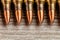 Closeup of rifle full metal jacket bullets in a row on wooden background with copy space