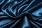 Closeup of rippled blue satin fabric texture background.