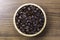 Closeup roasted coffee beans in wooden bowl isolated on wood table