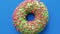 Closeup rotating sweet donut ring with green frosting and pink pastry topping. 4k Dragon RED camera