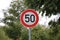 Closeup of a round fifty speed limit road sign on the road