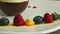 Closeup row of blueberry, raspberry, orange, and mint on white plate