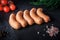 closeup row of five raw short thick sausages with dill and tomatoes