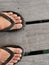 Closeup with rubber sandals and feet on wooden path.