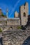 Closeup of a ruined wall of weathered stone bricks, towers and a flag in the background