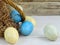 Closeup of a rustic Easter basket with brown paper grass and blue, green and yellow spotted or speckled eggs on a whitewashed