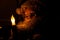 Closeup of a Santa Claus doll in front of a fake lit candle in a dark room